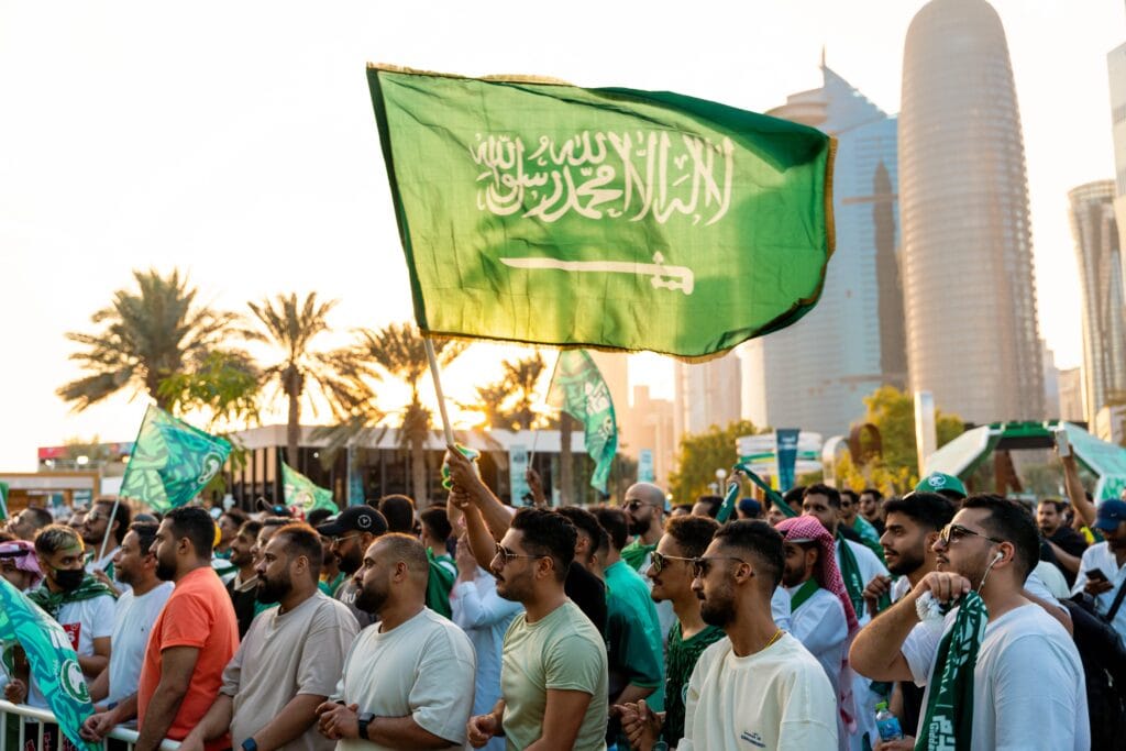 Crowd waving Saudi Arabian flags.